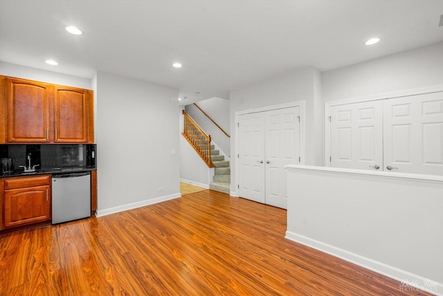 kitchen featuring backsplash, sink, dishwasher, and light wood-type flooring