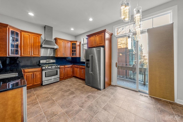 kitchen with pendant lighting, stainless steel appliances, tasteful backsplash, a notable chandelier, and wall chimney exhaust hood