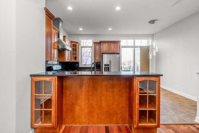 kitchen featuring tasteful backsplash, high quality fridge, plenty of natural light, kitchen peninsula, and stove