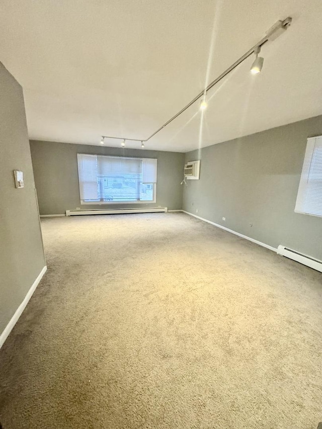 carpeted spare room with a baseboard heating unit, rail lighting, and a wall mounted AC