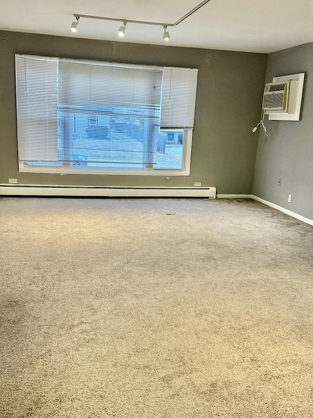 carpeted spare room featuring a baseboard radiator, rail lighting, and a wall mounted air conditioner