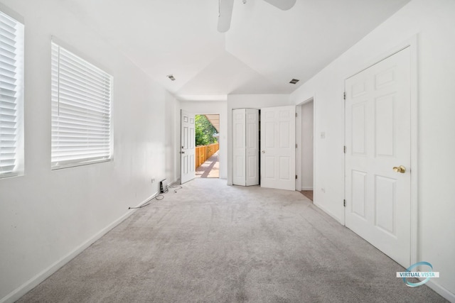 unfurnished bedroom with ceiling fan, vaulted ceiling, and light carpet