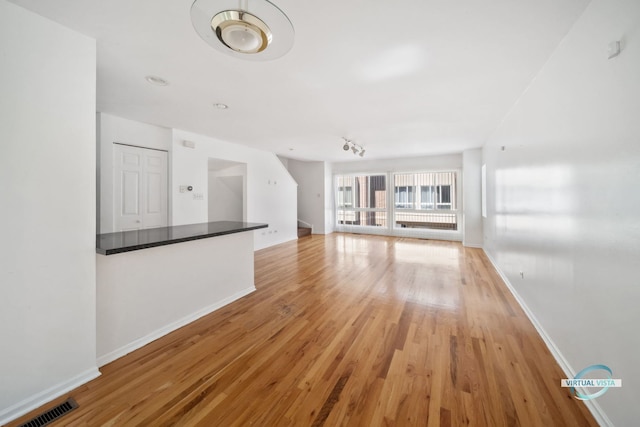 unfurnished living room with track lighting and light wood-type flooring