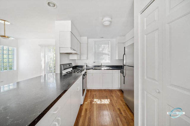 kitchen featuring sink, range with gas cooktop, stainless steel fridge, and white cabinets