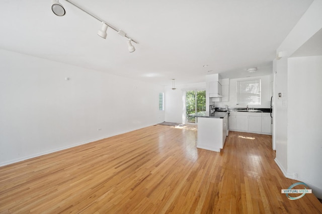 kitchen featuring sink, white cabinetry, hanging light fixtures, light hardwood / wood-style flooring, and a kitchen island