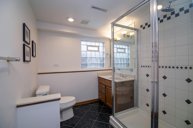 bathroom featuring vanity, tile patterned flooring, toilet, and walk in shower