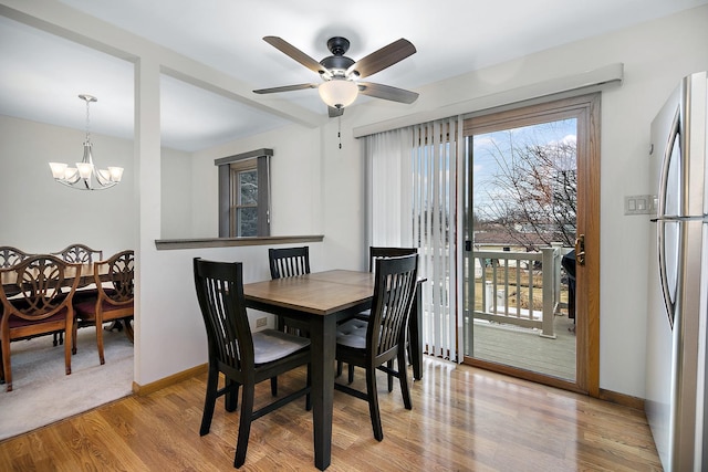 dining room featuring ceiling fan with notable chandelier and light hardwood / wood-style flooring