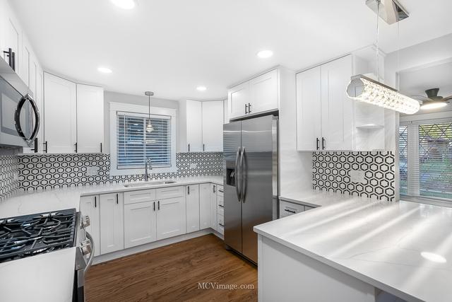 kitchen with white cabinetry, hanging light fixtures, and stainless steel appliances