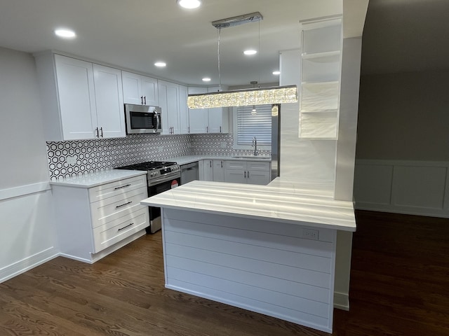 kitchen featuring appliances with stainless steel finishes, sink, pendant lighting, and white cabinets