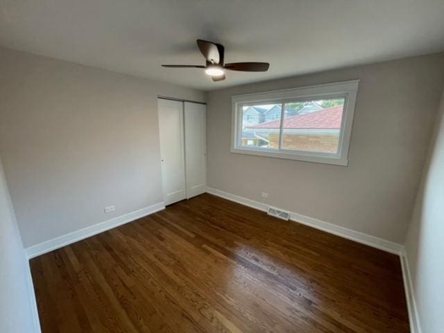 unfurnished bedroom featuring dark hardwood / wood-style flooring, ceiling fan, and a closet