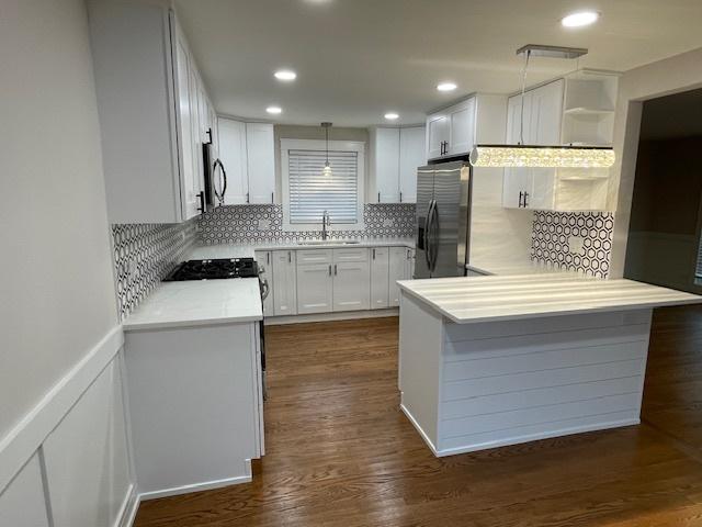 kitchen with sink, white cabinetry, tasteful backsplash, hanging light fixtures, and stainless steel fridge