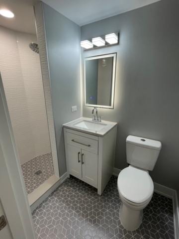 bathroom with vanity, a tile shower, and toilet