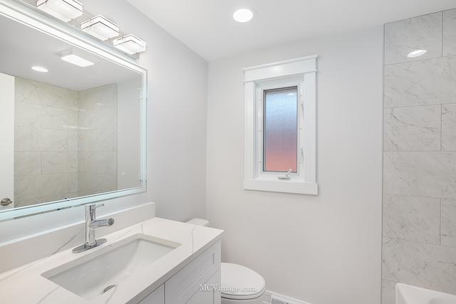 full bathroom featuring tiled shower / bath combo, vanity, and toilet