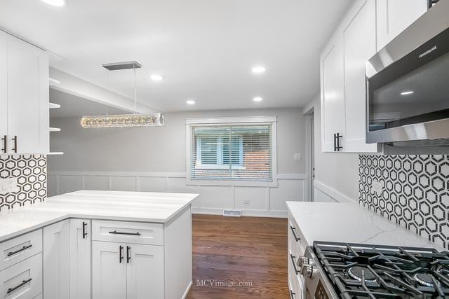 kitchen featuring appliances with stainless steel finishes, dark wood-type flooring, white cabinets, and decorative light fixtures