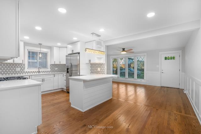 kitchen featuring light hardwood / wood-style flooring, stainless steel refrigerator with ice dispenser, white cabinets, decorative backsplash, and decorative light fixtures