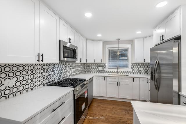 kitchen featuring appliances with stainless steel finishes, decorative light fixtures, white cabinetry, sink, and dark hardwood / wood-style flooring