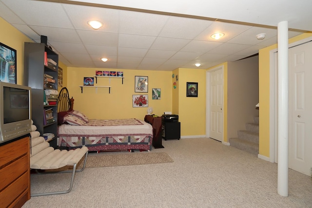 bedroom with a drop ceiling and light colored carpet