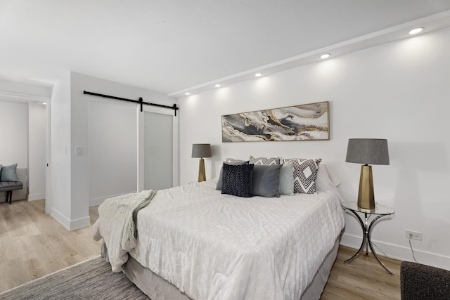 bedroom featuring a barn door and light hardwood / wood-style flooring