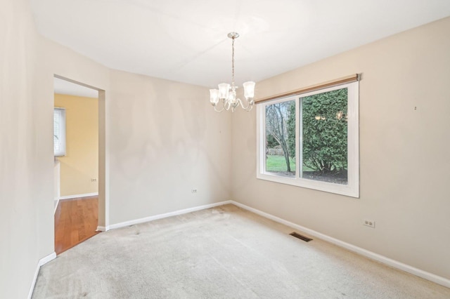 carpeted empty room featuring a notable chandelier