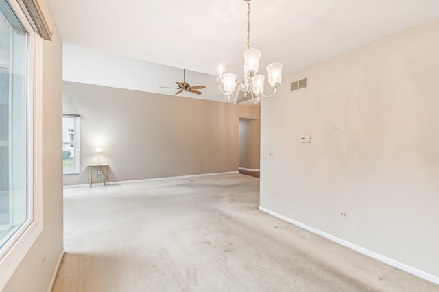 carpeted empty room featuring ceiling fan with notable chandelier and vaulted ceiling