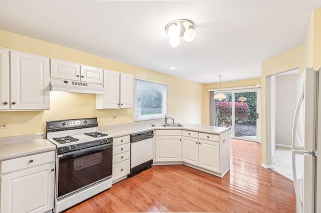 kitchen with sink, decorative light fixtures, kitchen peninsula, white appliances, and white cabinets