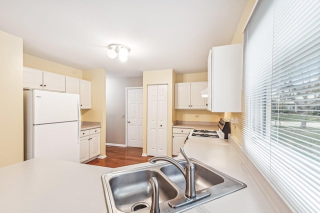 kitchen with sink, hardwood / wood-style flooring, stove, white refrigerator, and white cabinets