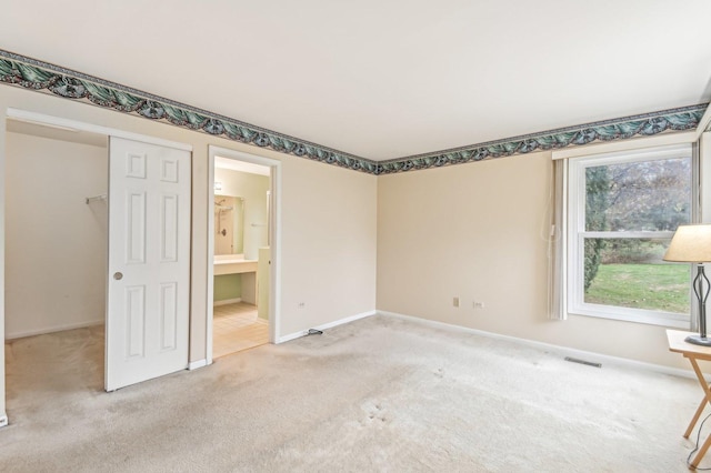 unfurnished bedroom with ensuite bath, carpet floors, and a closet