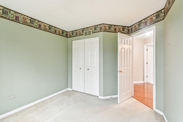 unfurnished bedroom with light colored carpet and a closet