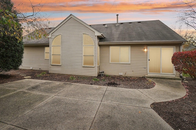 back house at dusk featuring a patio area