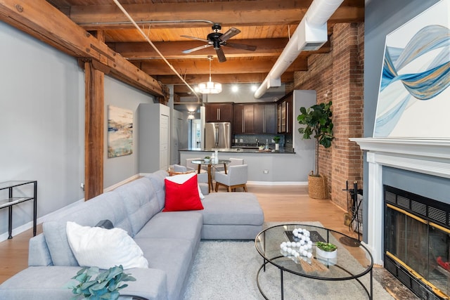 living room with a large fireplace, light wood-type flooring, wood ceiling, track lighting, and beam ceiling