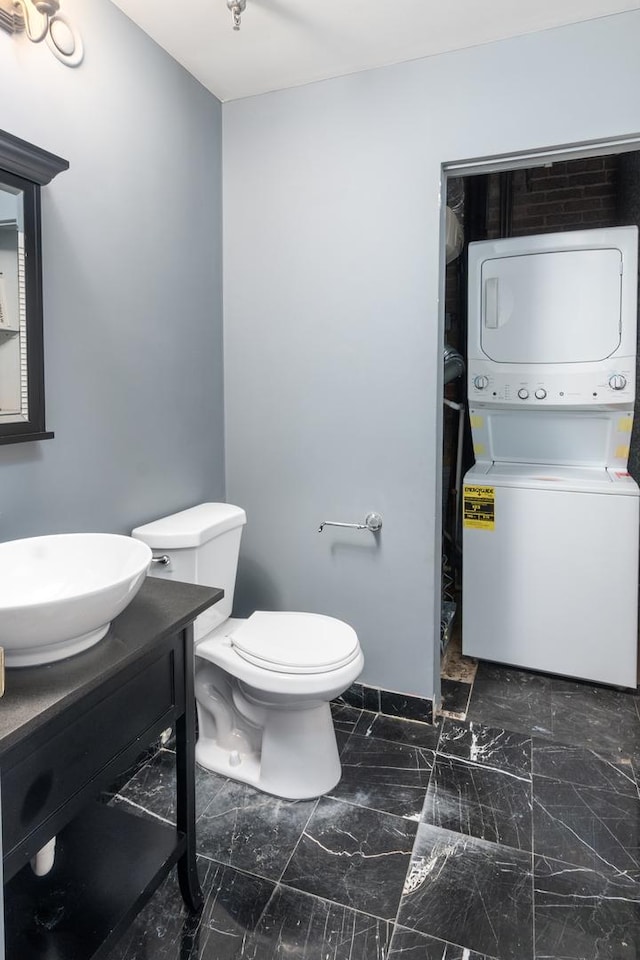 bathroom with vanity, stacked washer and dryer, and toilet