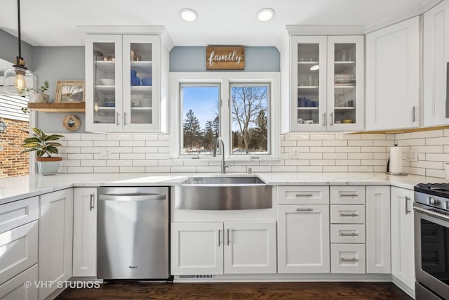 kitchen with light stone counters, appliances with stainless steel finishes, a sink, and white cabinetry