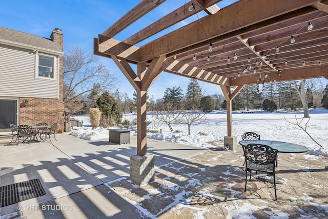 snow covered patio featuring a pergola and outdoor dining space