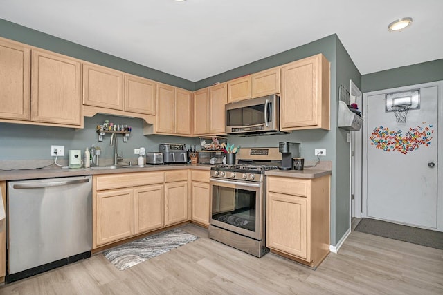 kitchen with sink, light wood-type flooring, stainless steel appliances, and light brown cabinets