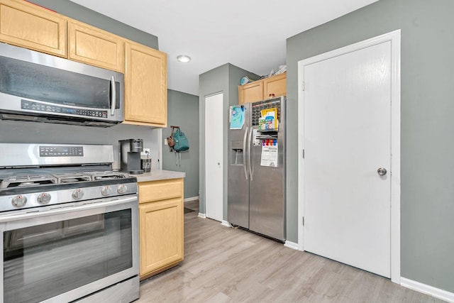 kitchen with appliances with stainless steel finishes, light brown cabinets, and light hardwood / wood-style floors