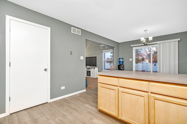 kitchen with an inviting chandelier, light brown cabinets, light wood-type flooring, and decorative light fixtures