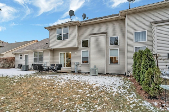 snow covered property with central AC unit and a patio area