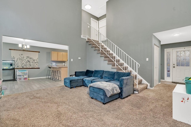 living room with a chandelier, light carpet, and a high ceiling