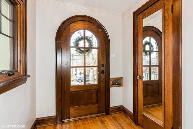 foyer with baseboards, light wood finished floors, a wealth of natural light, and crown molding