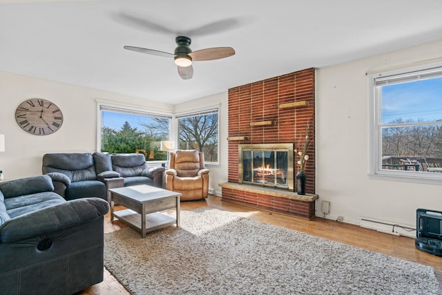 living room featuring a fireplace, hardwood / wood-style flooring, a baseboard radiator, and ceiling fan