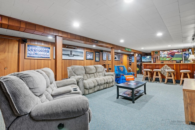 living room featuring carpet floors, bar, and wood walls