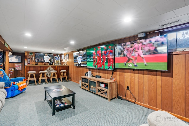 carpeted living room with wooden walls and bar area