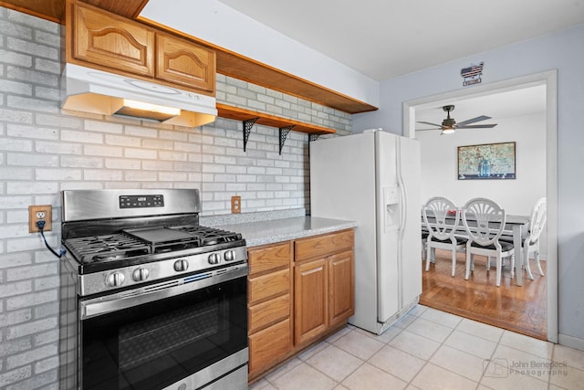 kitchen featuring light tile patterned flooring, decorative backsplash, white refrigerator with ice dispenser, ceiling fan, and gas range