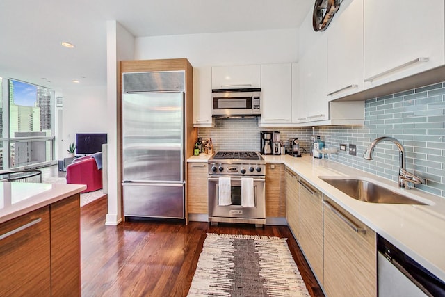 kitchen with sink, high end appliances, white cabinetry, tasteful backsplash, and dark hardwood / wood-style floors