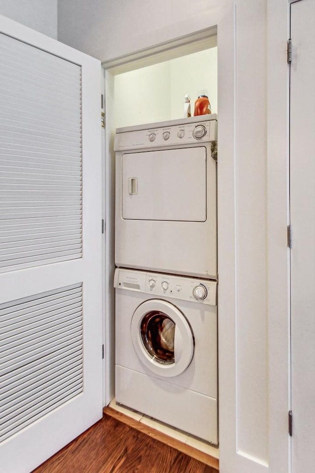 clothes washing area featuring dark wood-type flooring and stacked washing maching and dryer