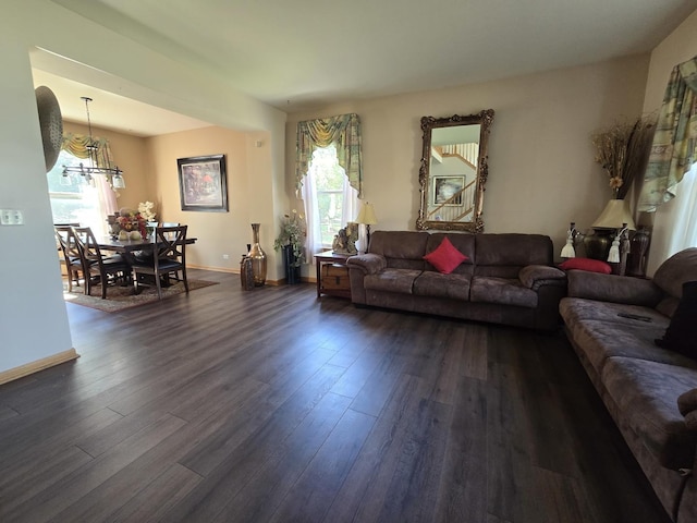 living room with an inviting chandelier, a wealth of natural light, and dark hardwood / wood-style floors