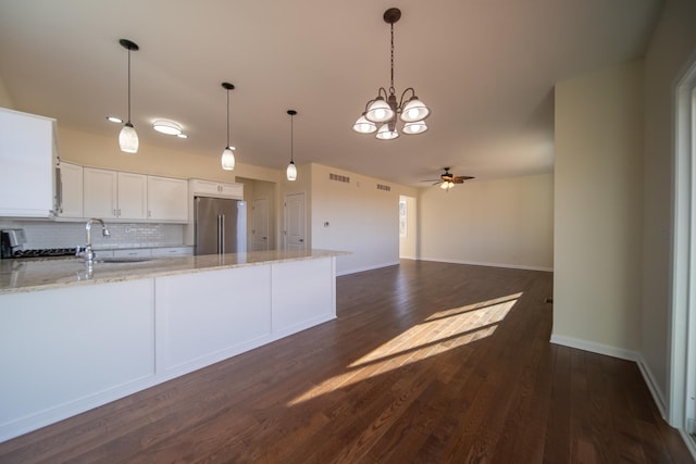 kitchen featuring high quality fridge, tasteful backsplash, white cabinets, hanging light fixtures, and light stone countertops