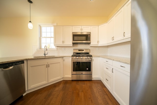 kitchen with pendant lighting, appliances with stainless steel finishes, sink, and white cabinets