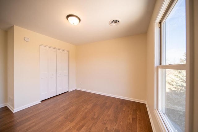 unfurnished bedroom with dark wood-type flooring and a closet