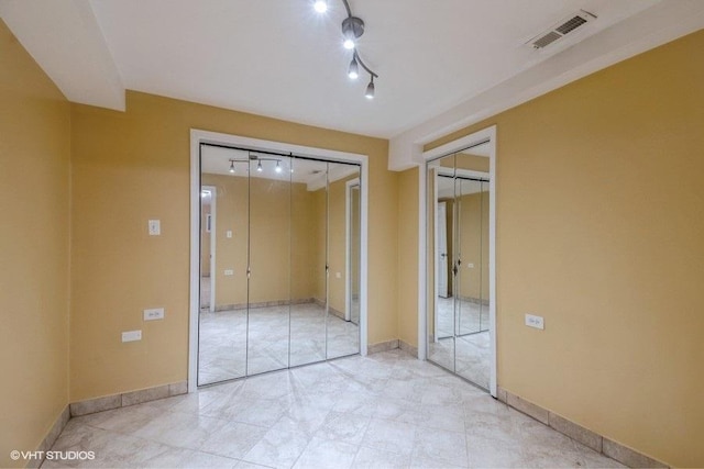 unfurnished bedroom featuring rail lighting